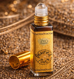 Roll-on perfume bottle with gold cap and decorative label on a textured gold background