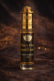 Gold and black perfume oil bottle on a textured brown background
